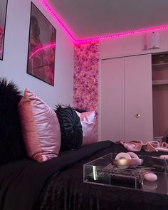 a bedroom with pink lights and black bedding, along with pictures on the wall