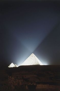 two pyramids in the distance with light coming from them