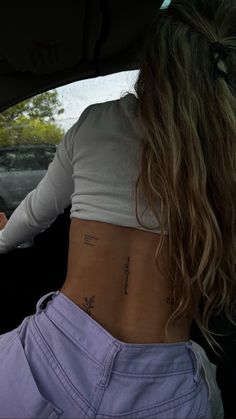 a woman sitting in the back seat of a car with tattoos on her lower back