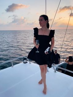 a woman standing on the back of a boat holding a wine glass