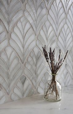 a vase filled with dried lavender sitting on top of a white marble counter next to a wall