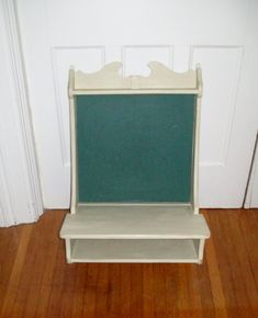 a small white shelf with a chalkboard on it in front of a door and wooden floor