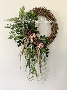a wreath hanging on the wall with flowers and greenery