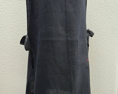 the back of a woman's black dress hanging on a wall with her hands in her pockets
