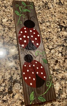 a wooden sign with ladybugs painted on it