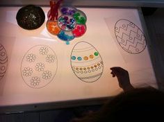 a child's hand is pointing at an easter egg drawing on a white board