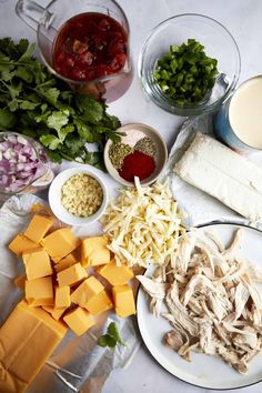 several different types of cheese and other ingredients on a white tablecloth with food in bowls