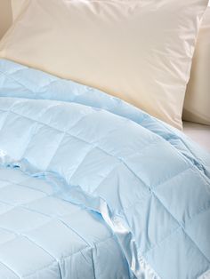 an unmade bed with white pillows and blue comforter