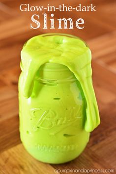 a mason jar filled with green slime sitting on top of a wooden table next to a text overlay that reads glow - in the dark slime