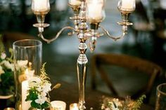 a candelabra filled with candles and flowers on top of a wooden table