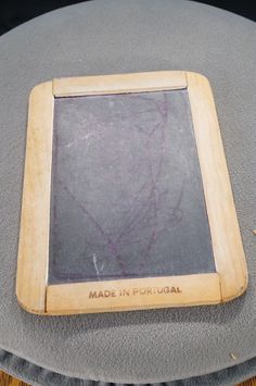a small wooden frame sitting on top of a gray cushion with writing written in it