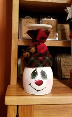a wooden shelf filled with christmas decorations and jars on top of it, including a snowman's hat