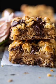 two pieces of chocolate chip cookie bars stacked on top of each other with flowers in the background