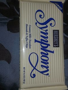 an unopened chocolate bar sitting on top of a blue and white bed sheet