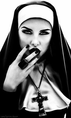 a woman with black nails and a nun outfit holding a cross in her hand while wearing a necklace