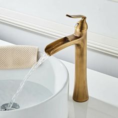 a gold faucet with water running from it's spout in a bathroom sink