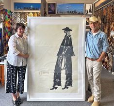 two people standing in front of a large framed art piece with an image of a man and woman