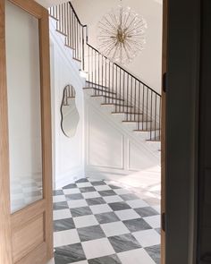 an open door leading to a white and black checkered floor with a chandelier