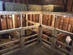 the inside of a barn with hay bales on the floor and in the stalls