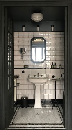 a bathroom with black and white tile walls, flooring and a pedestal sink in the middle