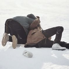 a person laying in the snow with their head on his back and one foot up