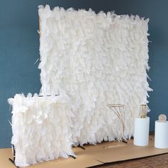 a large white feathered wall next to two rolls of toilet paper on a table