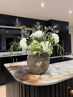 a vase filled with flowers sitting on top of a marble counter next to an oven