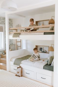 a young boy sitting on top of a bunk bed in a room with white walls