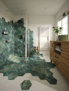a bathroom with green tiles on the floor and walls, along with a wooden cabinet