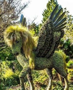 a horse made out of plants in the middle of some trees and bushes with long hair on it's back