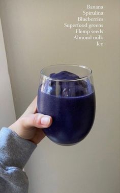 a person holding up a glass filled with blue liquid