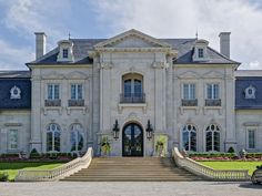 a large white mansion with stairs leading up to it's front door and windows