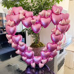 a heart shaped balloon arrangement in the shape of a planter on a glass table