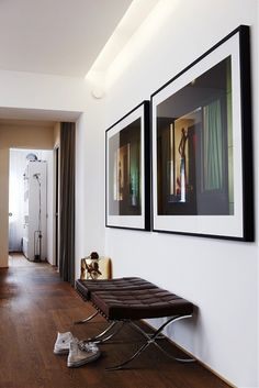 a hallway with pictures on the wall and a bench in front of it next to a pair of shoes