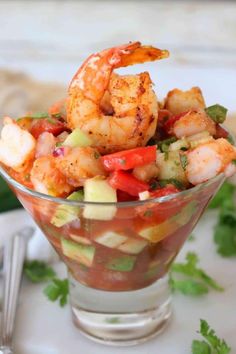 a glass bowl filled with shrimp salad and garnished with cilantro sauce