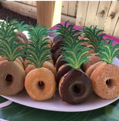 several donuts are arranged on a plate with pineapples in the middle and green leaves