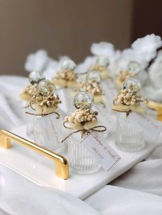 small glass vases with gold and silver decorations on a white tray, tied with twine
