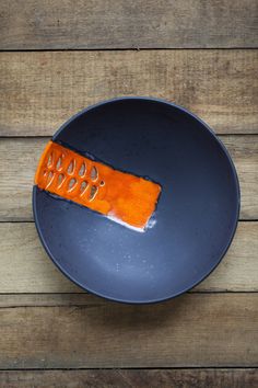 a blue plate topped with an orange piece of food on top of a wooden table