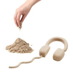 a hand is throwing sand into a pile and an earbuds are next to it