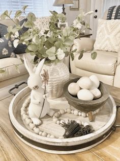 a living room with a white couch and table filled with eggs, plants and decorations