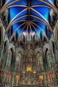 the inside of a cathedral with blue ceiling and stained glass windows