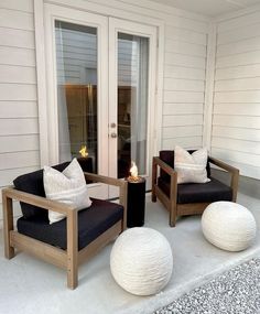 two chairs sitting on top of a patio next to a fire place with pillows around them
