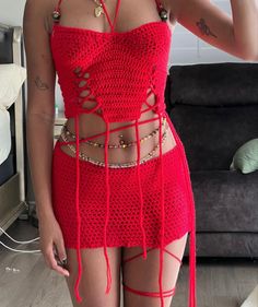 a woman wearing a red crochet dress and holding a cell phone