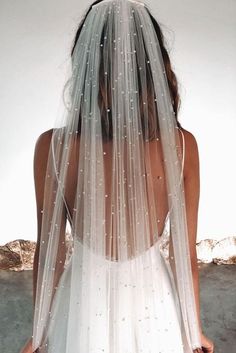 the back of a woman wearing a wedding veil with pearls on it's side