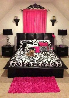 a black and white bed with pink rugs on the floor next to two nightstands