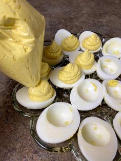hard boiled eggs on a glass plate with butter spread over them and in the background