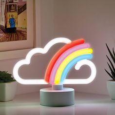 a rainbow shaped light sitting on top of a table next to a potted plant