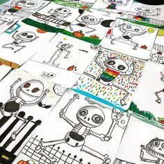 a table topped with lots of cartoon drawings on top of white paper covered in black ink