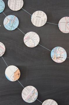 paper circles are strung on a blackboard with map pins attached to the strings and string