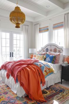 a bedroom with a large bed covered in colorful blankets and throw pillows on top of it